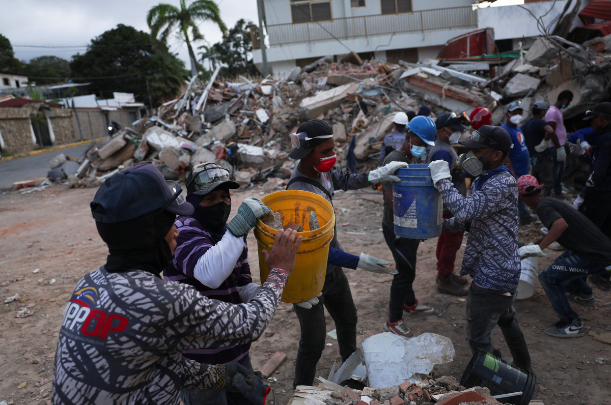 Rescuers pass rubble in buckets as they search through debris in the aftermath of the June 24 earthquakes, in La Guaira, Venezuela, July 4, 2026. REUTERS/Pablo Sanhueza