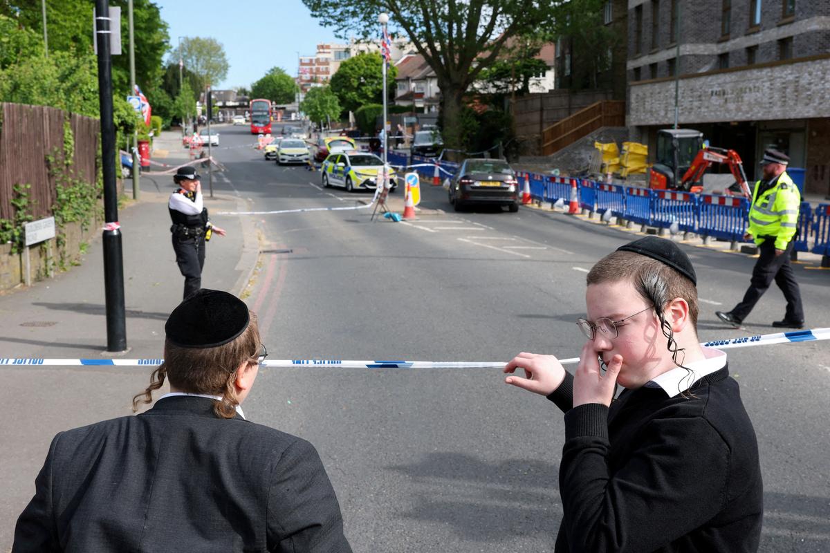 FILE PHOTO: Orthodox Jews stand by a police cordon, after a man was arrested following a stabbing incident in the Golders Green area, which is home to a large Jewish population, in London, Britain, April 29, 2026. REUTERS/Hannah McKay/File Photo