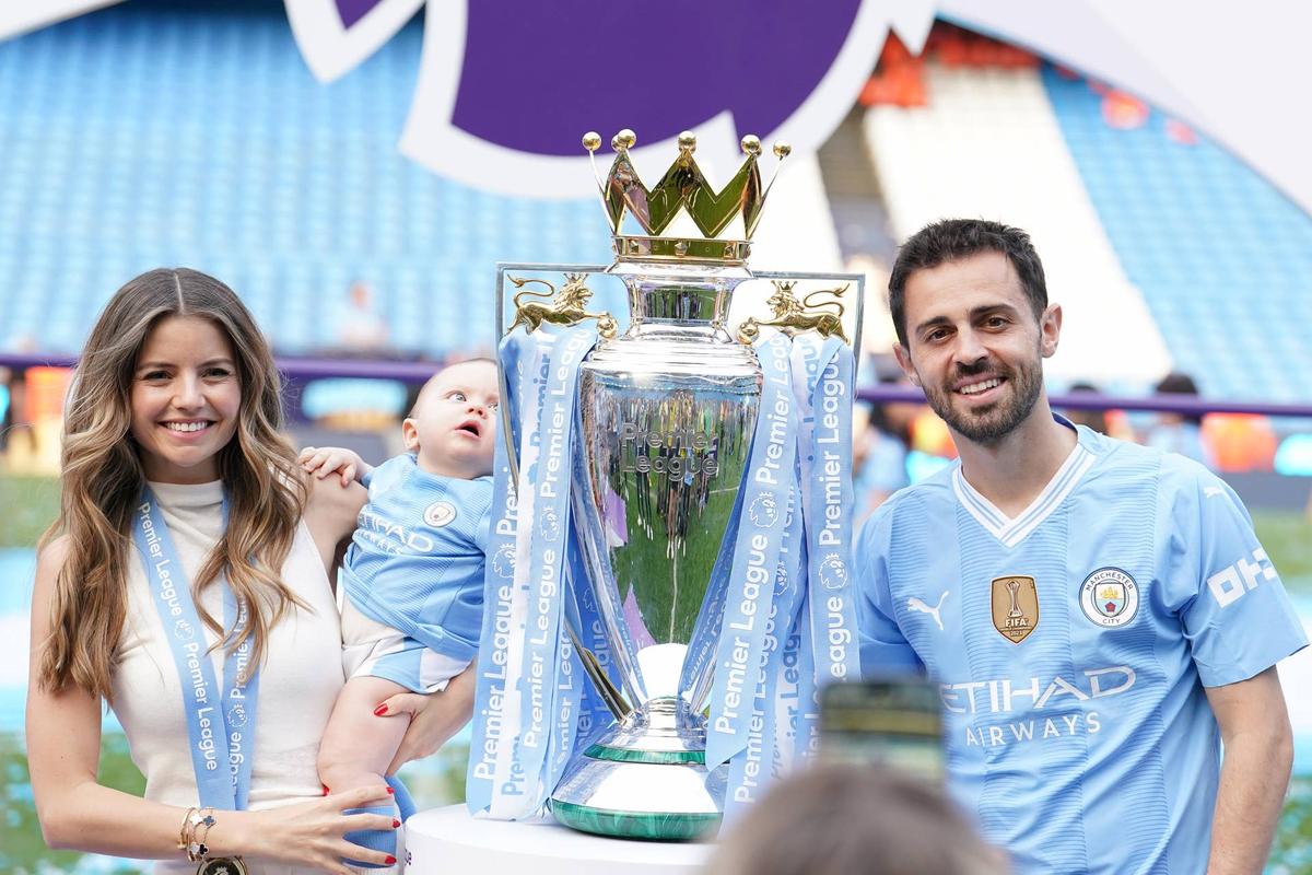  Manchester City's Bernardo Silva, his wife Ines Tomaz, and his child, pose with the Premier League trophy/ Photo by Martin Rickett/PA Images via Getty Images