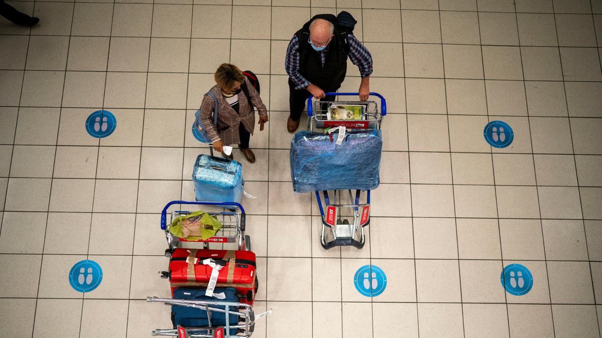 Dos personas esperan en el aeropuerto OR Tambo de Johannesburgo, Sudáfrica, el 26 de noviembre de 2021. (AP Foto/Jerome Delay)