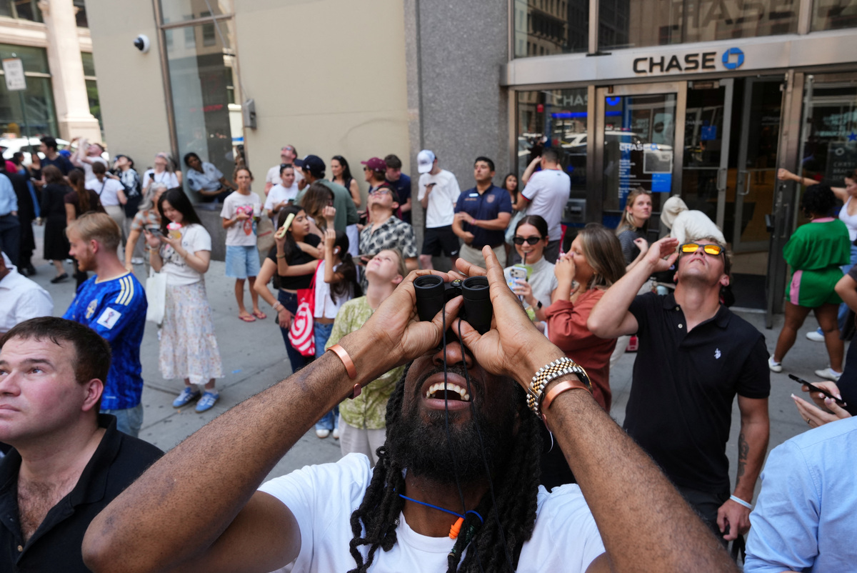People look up at two people displaying a banner as they stage a protest atop the Empire State Building in the Manhattan borough of New York, U.S., July 1, 2026.  REUTERS/Adam Gray