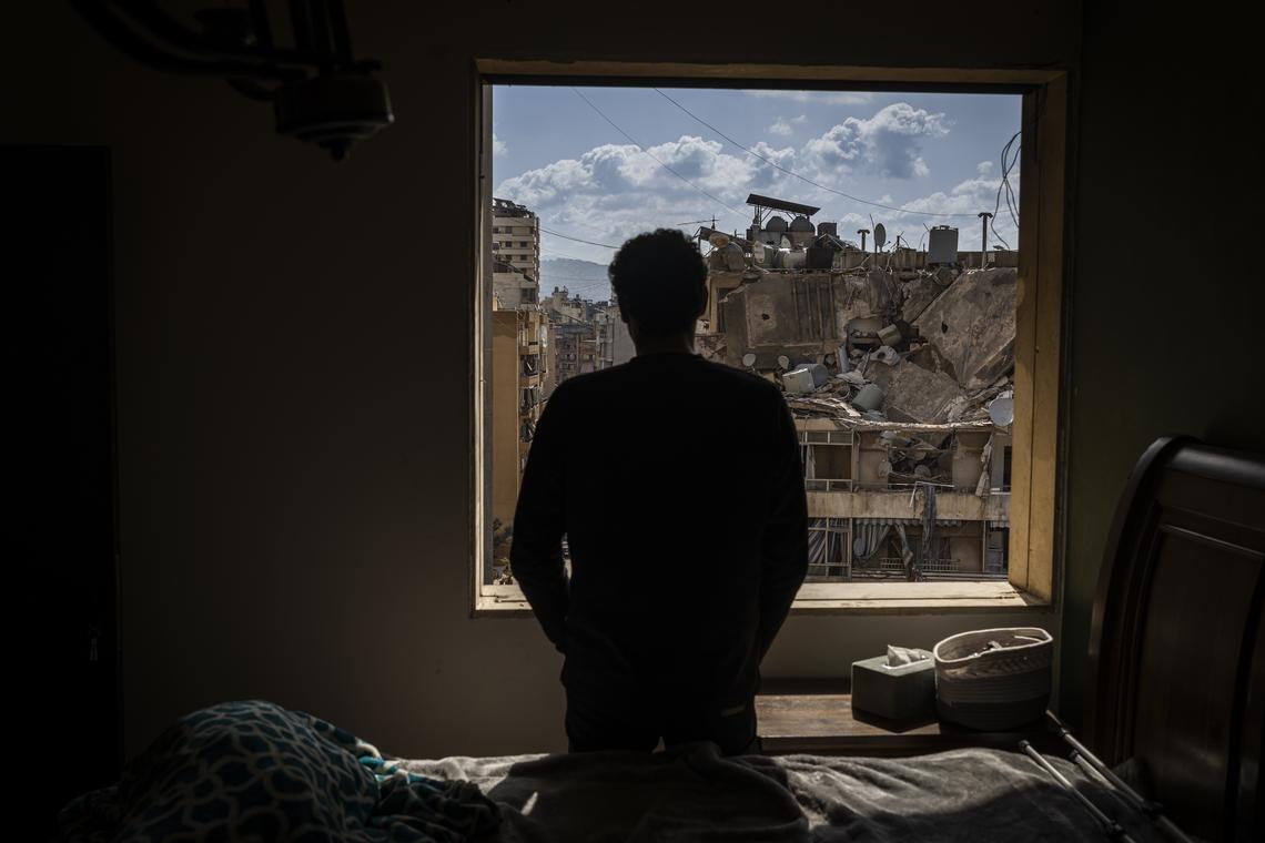 A man looks out from his apartment over the wreckage in his neighborhood near the Corniche, the seaside promenade, in Beirut, Lebanon, on Monday, April 13, 2026. According to the Lebanese government, more than 2,000 people have been killed in the country since the Iran-backed militia Hezbollah fired on northern Israel in early March, prompting a widening Israeli ground invasion. (Diego Ibarra Sánchez/The New York Times)