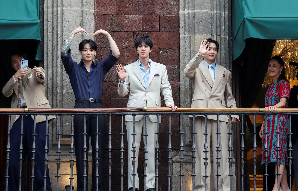 FILE PHOTO: Members of South Korean Kpop boy band BTS and Mexico's President Claudia Sheinbaum react as they stand on a balcony of the National Palace ahead of a series of concerts on the BTS World Tour "Arirang" in Mexico City, Mexico, May 6, 2026. REUTERS/Luis Cortes/File Photo