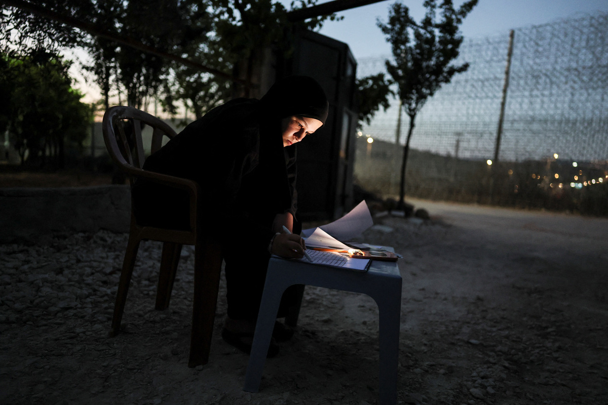 Amal Foqahaa, 13, draws a picture of the tall metal fencing installed by the Israeli military that closed off four of the five entrances to her town and runs directly past her house, in Sinjil, near Ramallah, in the Israeli-occupied West Bank, June 26, 2026. REUTERS/Ammar Awad