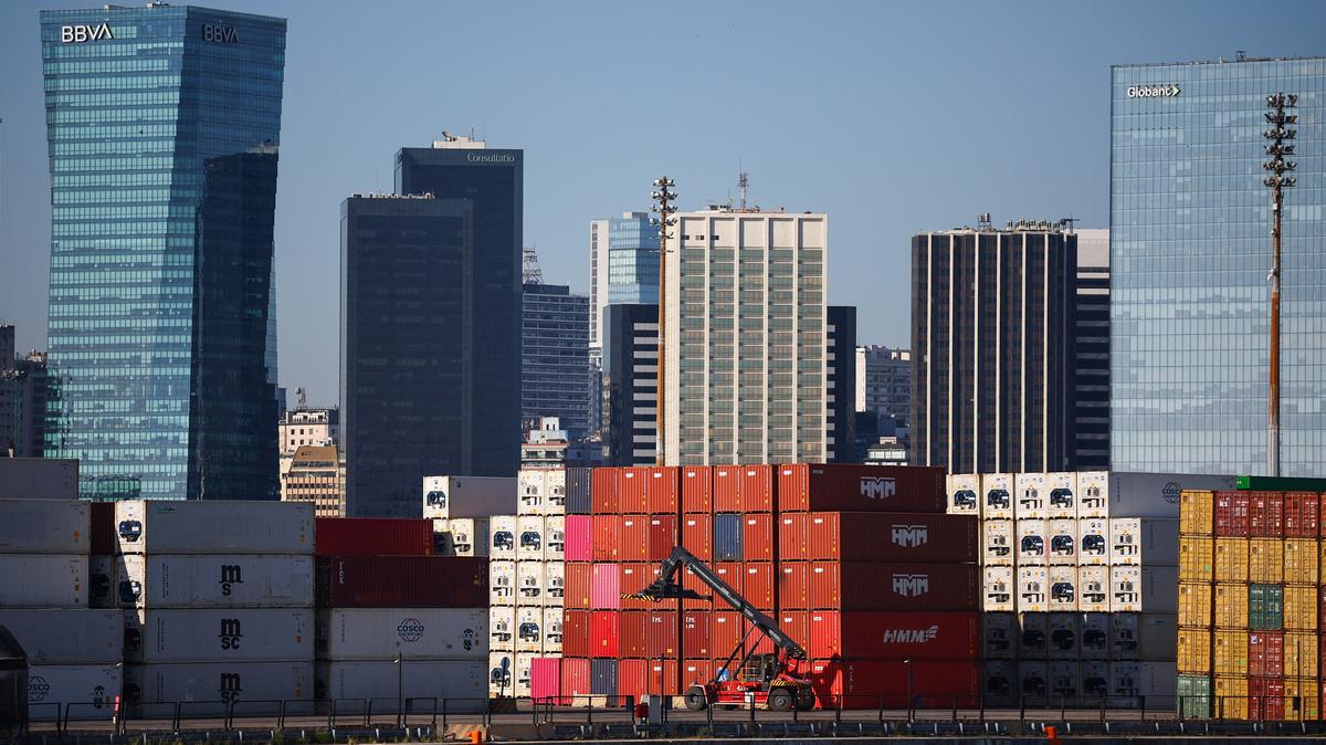 Stacks of shipping containers next to a reach stacker with office buildings in the background, at the port of Buenos Aires, Argentina, January 15, 2026. REUTERS/Agustin Marcarian