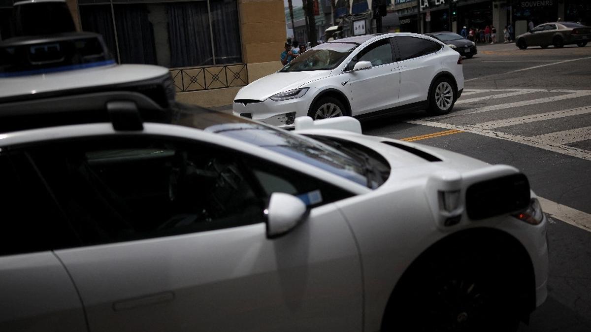 A Tesla drives by a Waymo self-driving car in Los Angeles, California, U.S., May 12, 2025. REUTERS/Daniel Cole