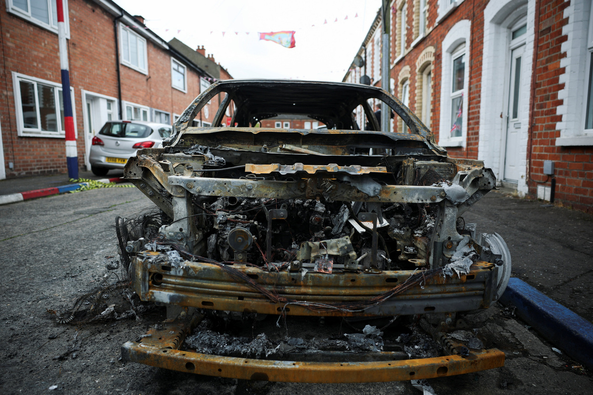 A burnt car on a street in the aftermath of anti-immigrant protests following a knife attack on June 8, which left a man seriously injured and prompted police to declare a critical incident, at Lendrick Street, east Belfast, Northern Ireland, June 10, 2026. REUTERS/Isabel Infantes