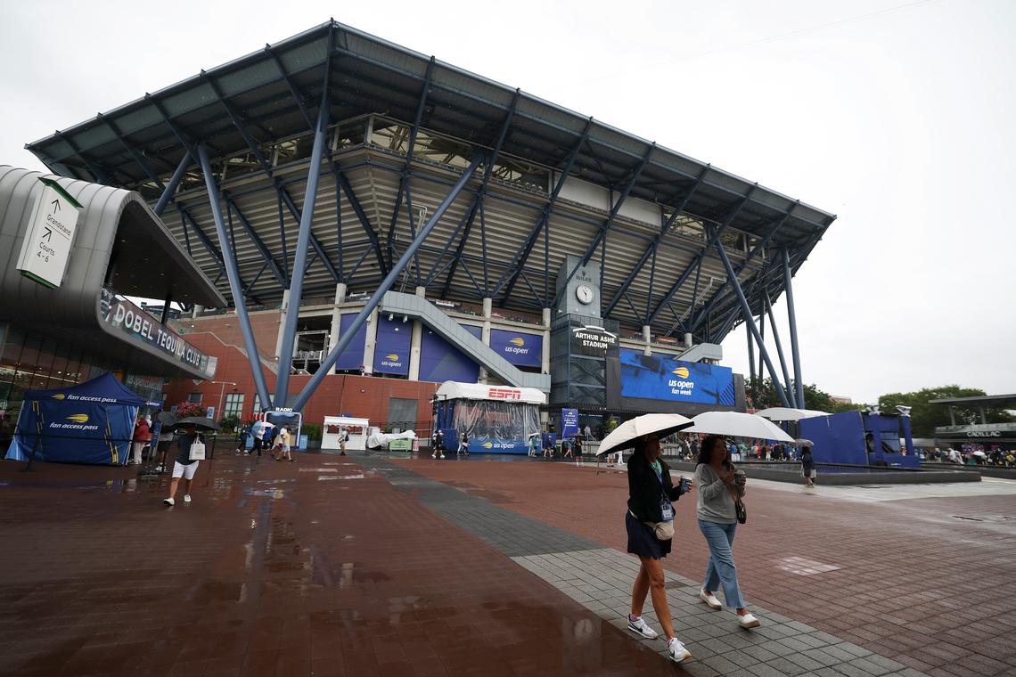 NEW YORK, NEW YORK - AUGUST 20: Fans walk in the rain carrying umbrellas past  Arthur Ashe stadium prior to the start of the US Open  at USTA Billie Jean King National Tennis Center on August 20, 2025 in New York City. (Photo by Al Bello/Getty Images)