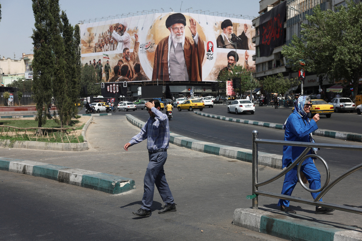 FILE PHOTO: People walk past a billboard featuring images of Iran's late Supreme Leader Ayatollah Ali Khamenei in Tehran, Iran, July 13, 2026. Majid Asgaripour/WANA (West Asia News Agency) via REUTERS/File Photo
