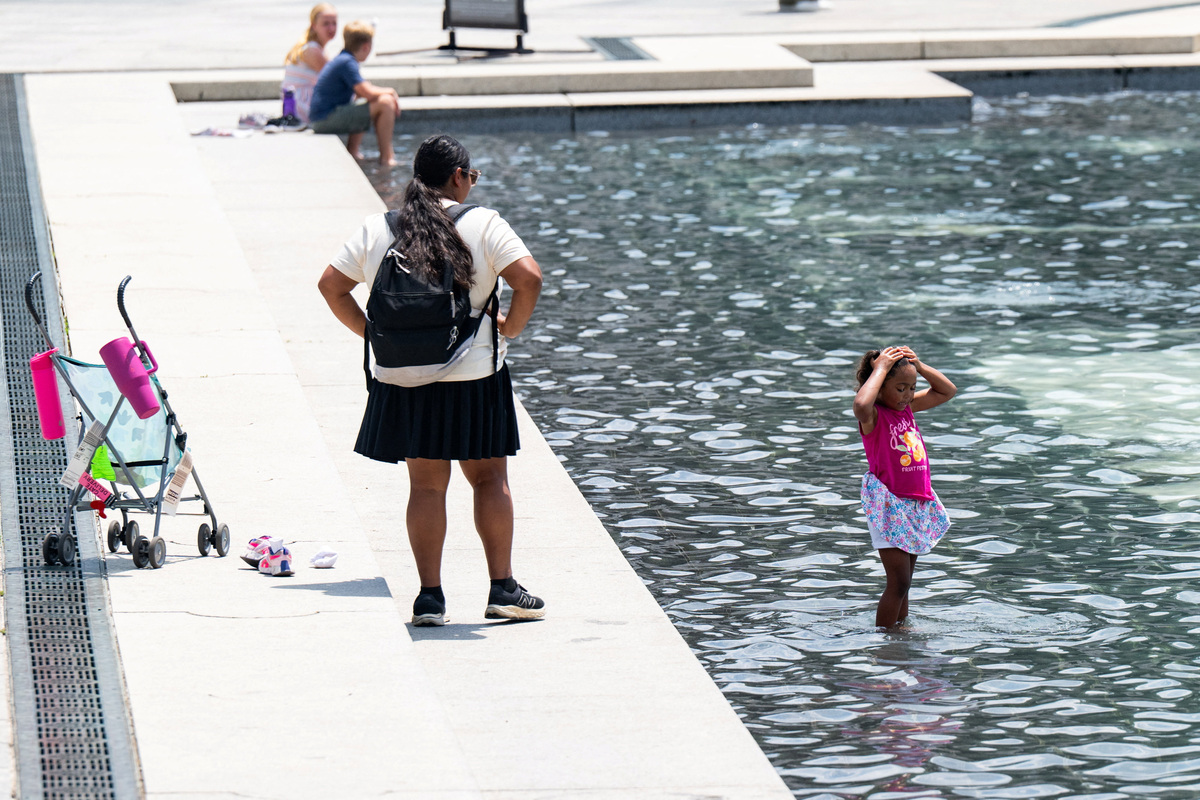 A girl splashes water onto herself at the World War II Memorial amid a heatwave in Washington, D.C., U.S., July 1, 2026. REUTERS/Annabelle Gordon