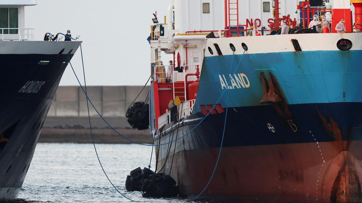Workers in personal protective equipment (PPE) stand aboard a tanker next to the cruise ship MV Hondius,  affected by a hantavirus outbreak, at the port of Granadilla de Abona, in Tenerife, Spain, May 11, 2026. REUTERS/Hannah McKay