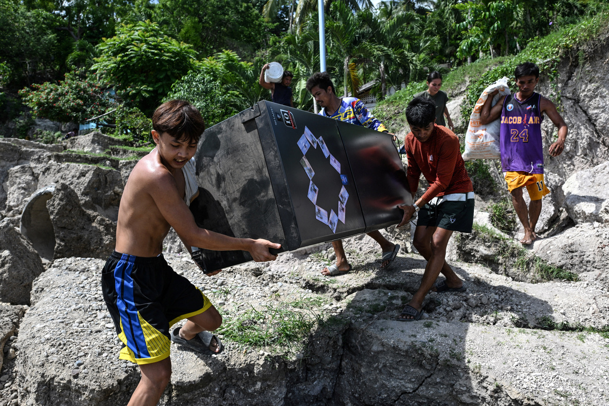 People living on the mountainside carry their belongings as they evacuate after a landslide following the magnitude 7.8 quake in Barangay Kapatan, Glan, Sarangani province, southern Philippines, June 10, 2026. REUTERS/Noel Celis