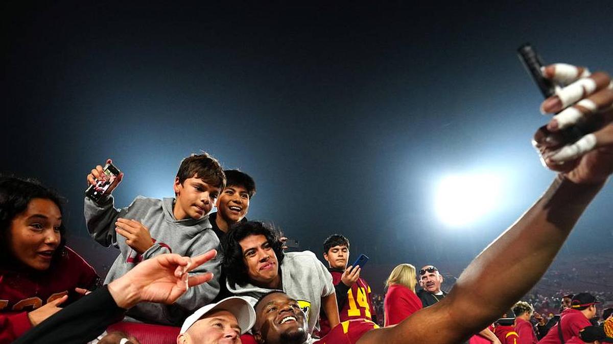  Nov 29, 2025; Los Angeles, California, USA; Southern California Trojans head coach Lincoln Riley (right) and defensive tackle Jahkeem Stewart (4) pose with fans after the game against the UCLA Bruins at United Airlines Field at Los Angeles Memorial Coliseum. Mandatory Credit: Kirby Lee-Imagn Images | Kirby Lee-Imagn Images 