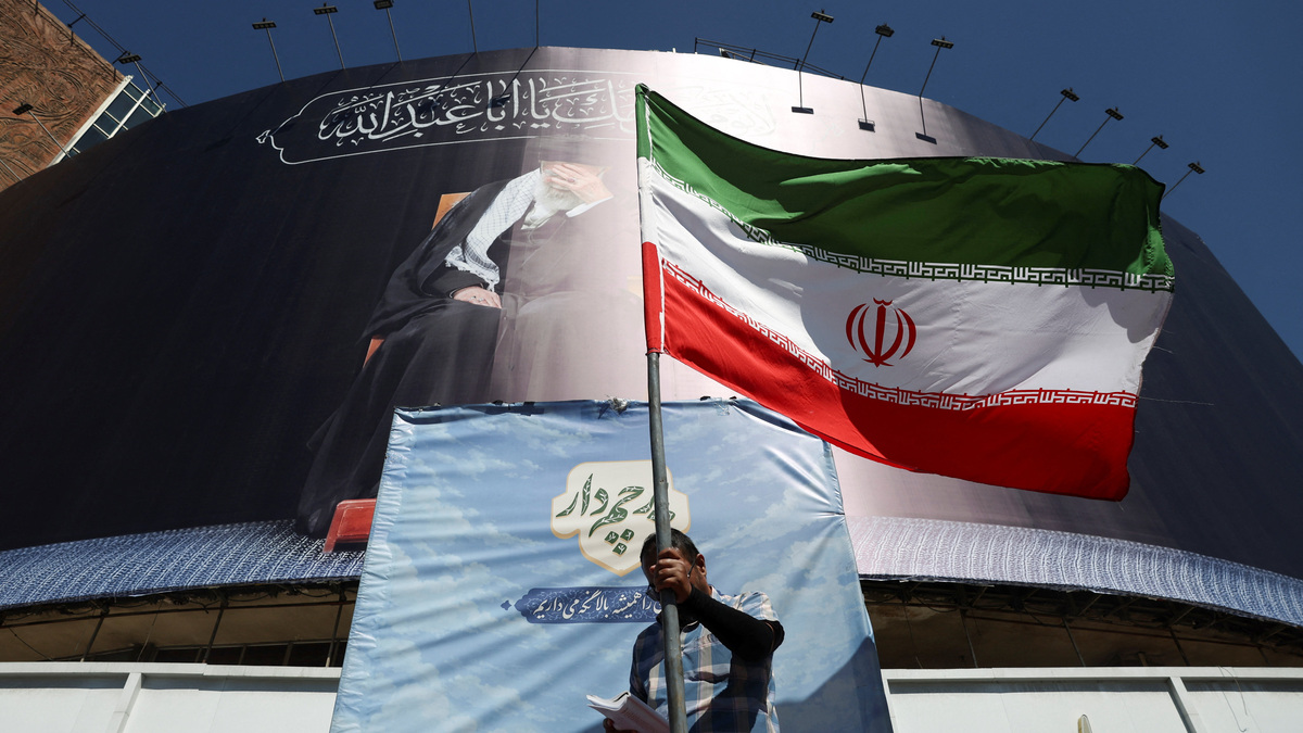 A man holds an Iranian flag on a street, after U.S. and Iranian officials said they had reached a deal to end their war and reopen the Strait of Hormuz, in Tehran, Iran, June 15, 2026. Majid Asgaripour/WANA (West Asia News Agency) via REUTERS
