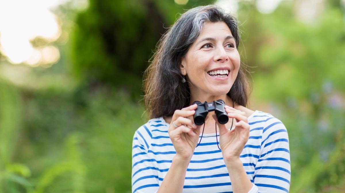 Hispanic woman using binoculars outdoors