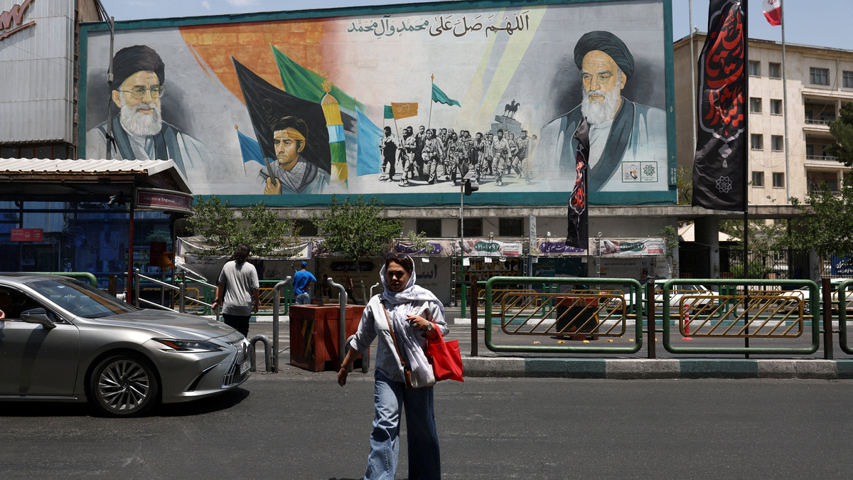 A woman walks near a mural depicting the late leader of the Islamic Revolution, Ayatollah Ruhollah Khomeini, and Iran's late Supreme Leader Ayatollah Ali Khamenei on June 18 on a street in Tehran, Iran.