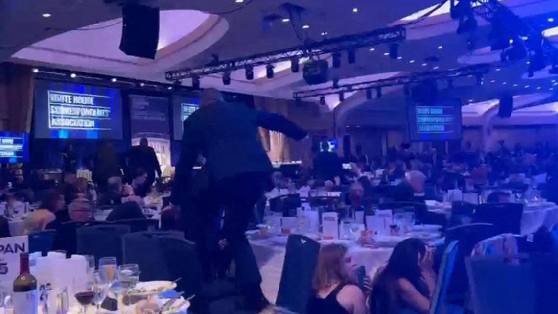 A screen grab taken from a video filmed by an AFP reporter shows armed agents climbing over chairs as they move to the stage after loud bangs were heard during the White House Correspondents' dinner at the Washington Hilton in Washington, D.C., on Saturday April 25, 2026. Shots were fired as U.S. President Donald Trump attended a press dinner in Washington on Saturday night, witnesses and AFP reporters confirmed. (Danny Kemp and AFPTV teams/AFP/Getty Images/TNS)