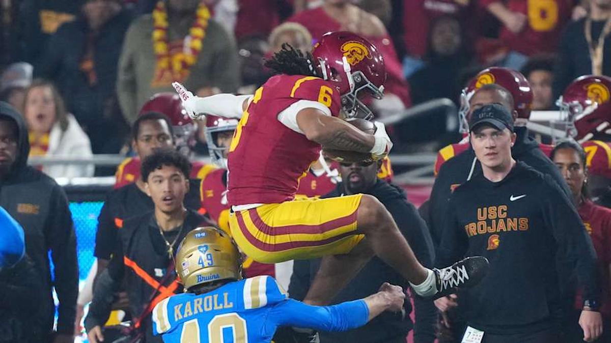  Nov 29, 2025; Los Angeles, California, USA; Southern California Trojans wide receiver Makai Lemon (6) hurdles UCLA Bruins punter Will Karoll (49) as linebacker Scott Taylor (20) watches in the second half at United Airlines Field at Los Angeles Memorial Coliseum. Mandatory Credit: Kirby Lee-Imagn Images | Kirby Lee-Imagn Images 