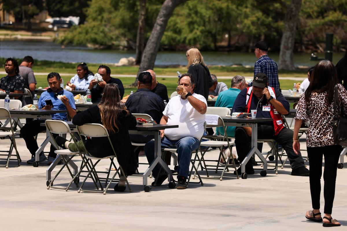 People eat meals at tables set up outside a shelter for evacuees from an area affected by a chemical incident involving a leaking tank of methyl methacrylate, a flammable liquid used in the aerospace industry, in Fountain Valley, California, U.S., May 23, 2026. The incident occurred in Garden Grove. REUTERS/David Swanson