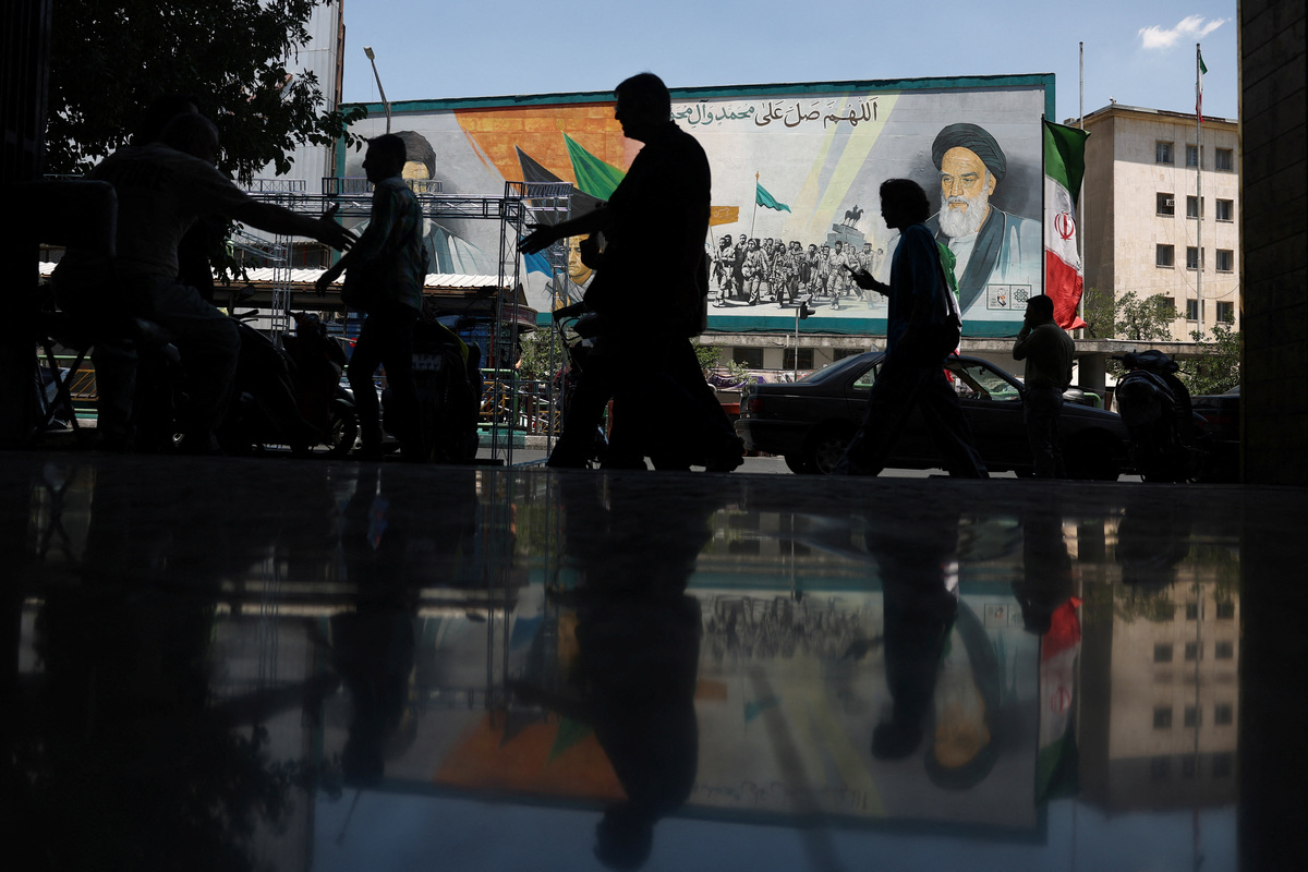 People walk near a mural depicting the late leader of the Islamic Revolution, Ayatollah Ruhollah Khomeini, and Iran's late Supreme Leader Ayatollah Ali Khamenei, on a street in Tehran, Iran, June 14, 2026. Majid Asgaripour/WANA (West Asia News Agency) via REUTERS