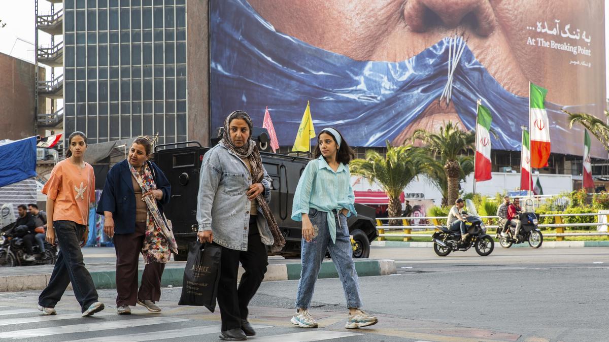 People pass near a billboard showing the closure of the Strait of Hormuz over President Donald Trump's face with a message reading "At the Breaking Point" in Tehran, May 2, 2026. President Trump on Thursday said his administration had had "very good talks" with Tehran in the last 24 hours. An Iranian official said an American plan to end the war was under review.