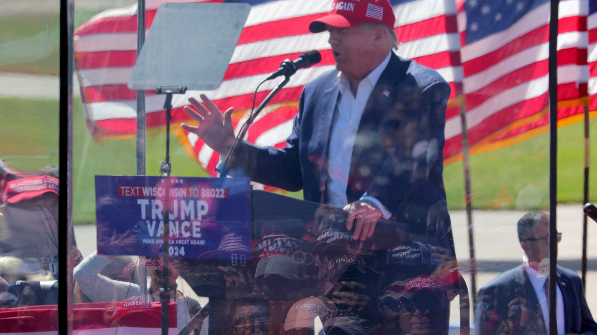 People are reflected in protective glass as they listen to Republican presidential nominee and former U.S. President Donald Trump as he speaks during a rally in Mosinee, Wisconsin, U.S. September 7, 2024. REUTERS/Brian Snyder