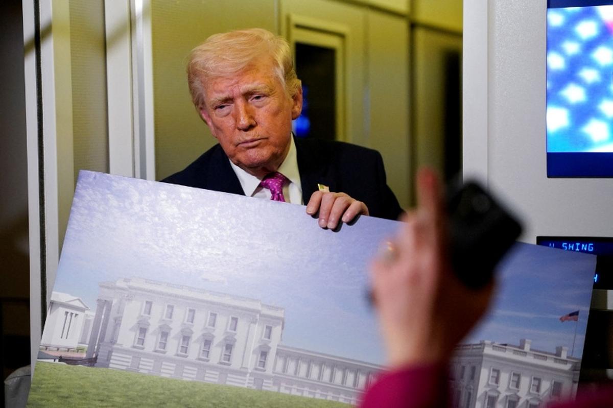 FILE PHOTO: A member of the media raises her hand for a question as U.S. President Donald Trump talks while holding up renderings of the planned White House ballroom, aboard Air Force One en route to Joint Base Andrews, Maryland, U.S., March 29, 2026. REUTERS/Elizabeth Frantz/File Photo