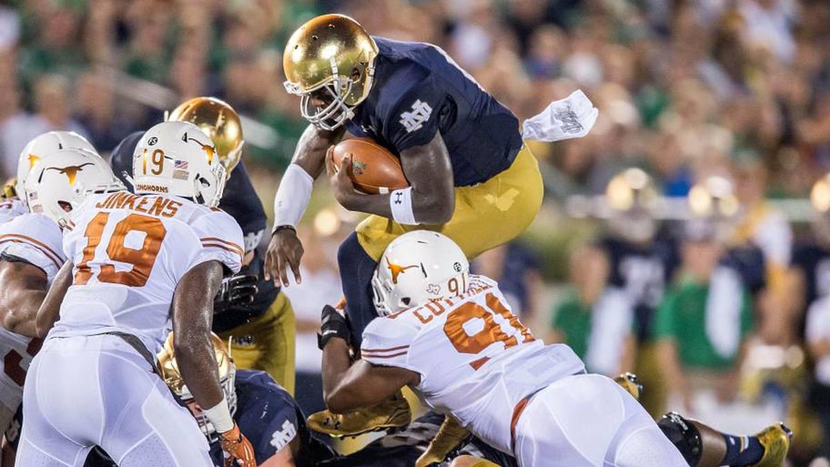  Sep 5, 2015; South Bend, IN, USA; Notre Dame Fighting Irish quarterback Malik Zaire (8) leaps over Texas Longhorns defensive end Bryce Cottrell (91) in the third quarter at Notre Dame Stadium. Notre Dame won 38-3. | Matt Cashore-Imagn Images 