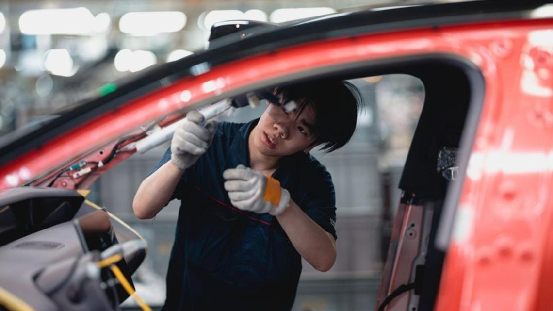 A laborer works on an assembly line during the organized press tour in the AVATR EV factory, in Chongqing, China. Photo by ALEX PLAVEVSKI / EPA