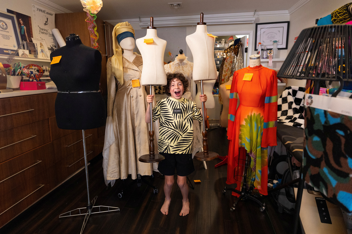 Max Alexander, 10, a fashion designer who recently debuted his first runway show in Paris, holds up two mannequins as he poses for a picture with mannequins labeled with Post-it notes in his studio at his parents' home in Los Angeles, California, U.S., June 5, 2026. REUTERS/Mike Blake
