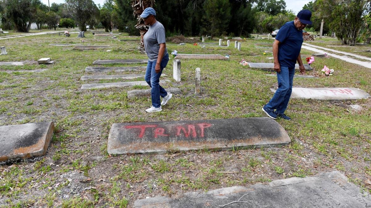 Family members of those buried at the Old Memphis Cemetery, a predominantly African-American cemetery in Palmetto, walk near a tomb with the word "Trump" spray-painted on it as they inspect their loved ones’ graves, after 17 gravesites and several headstones were vandalized in Palmetto, Florida, U.S., May 14, 2026. Authorities say “Trump” and “DeSantis” were spray-painted in red across multiple tombs as police continue investigating the incident. REUTERS/Octavio Jones