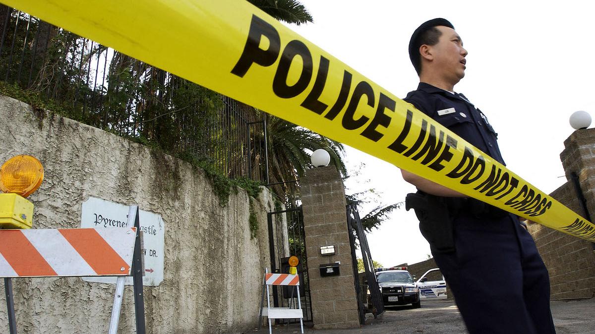 A policeman stands outside the Alhambra, CA, home of record producer Phil Spector, 04 February 2003.  Spector was booked for investigation of murder 02 February 2003 in the deadly shooting of Lana Clarkson, 40, whose body was found at the house with the gun used in the shooting.  Spector was taken into custody and released 03 February after posting a USD 1 million bond.  AFP PHOTO/Lucy NICHOLSON (Photo by LUCY NICHOLSON / AFP)