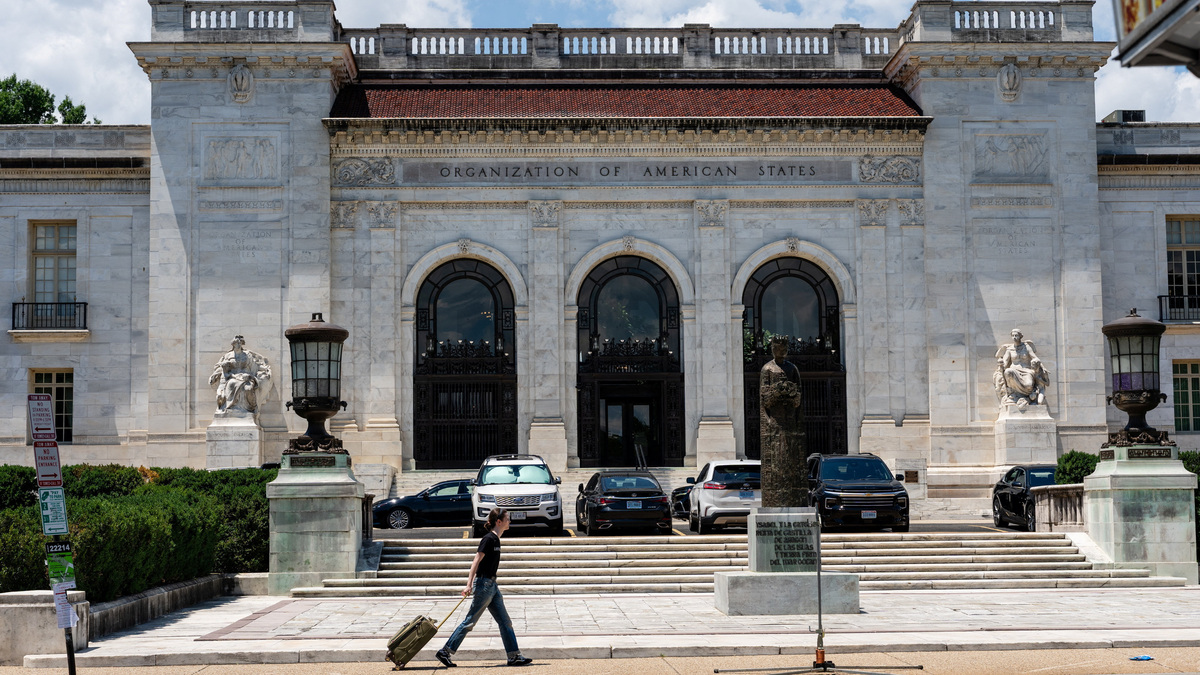 A person pulls a rolling suitcase as they walk by the Organization of American States (OAS) headquarters in Washington, D.C., U.S., June 17, 2026. REUTERS/Eric Lee
