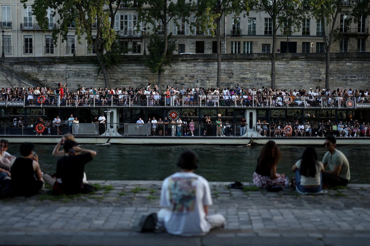 A boat passes people sitting on the banks of the Seine River, as temperatures reached up to 35 degrees during a period of hot weather in Paris, France, May 25, 2026. REUTERS/Tom Nicholson