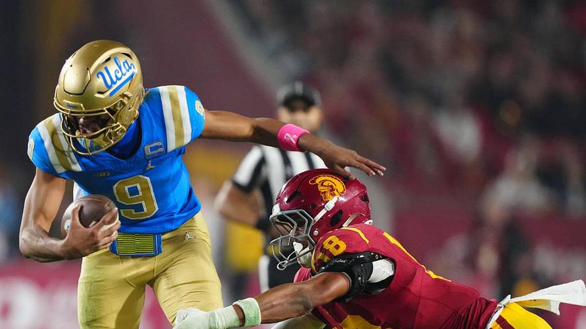  Nov 29, 2025; Los Angeles, California, USA; UCLA Bruins quarterback Nico Iamaleava (9) is tackled by Southern California Trojans linebacker Eric Gentry (18) in the second half at United Airlines Field at Los Angeles Memorial Coliseum. Mandatory Credit: Kirby Lee-Imagn Images | Kirby Lee-Imagn Images 