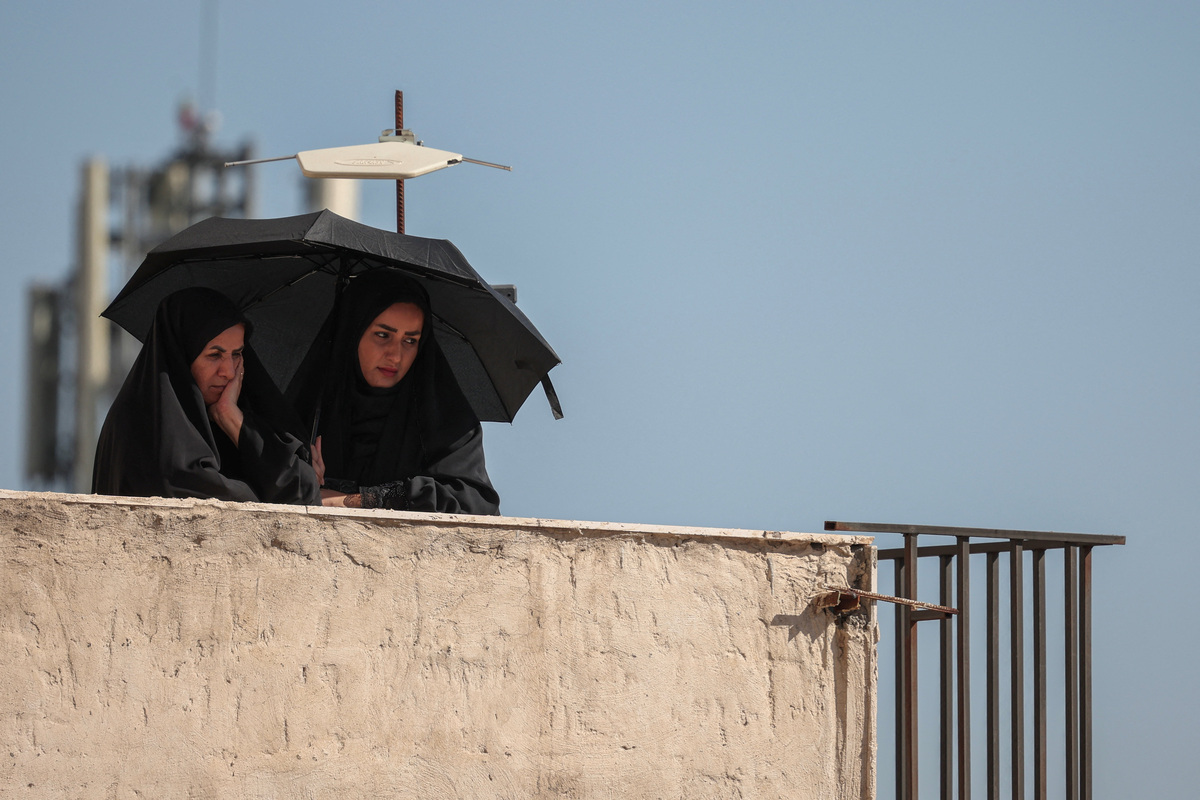 Two mourners overlook a funeral procession on the day of the burial of Iran's late Supreme Leader Ayatollah Ali Khamenei, who was killed on February 28 in Israeli and U.S. airstrikes, in Mashhad, Iran, July 9, 2026. REUTERS/Alkis Konstantinidis