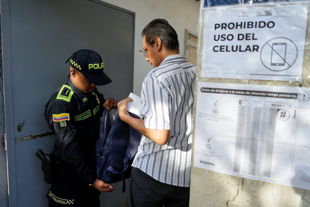 Un agente de policía revisa el bolso de un hombre en un colegio electoral el día de la segunda vuelta de las elecciones presidenciales en Barranquilla (Colombia). 21 junio 2026. REUTERS/Charlie Cordero