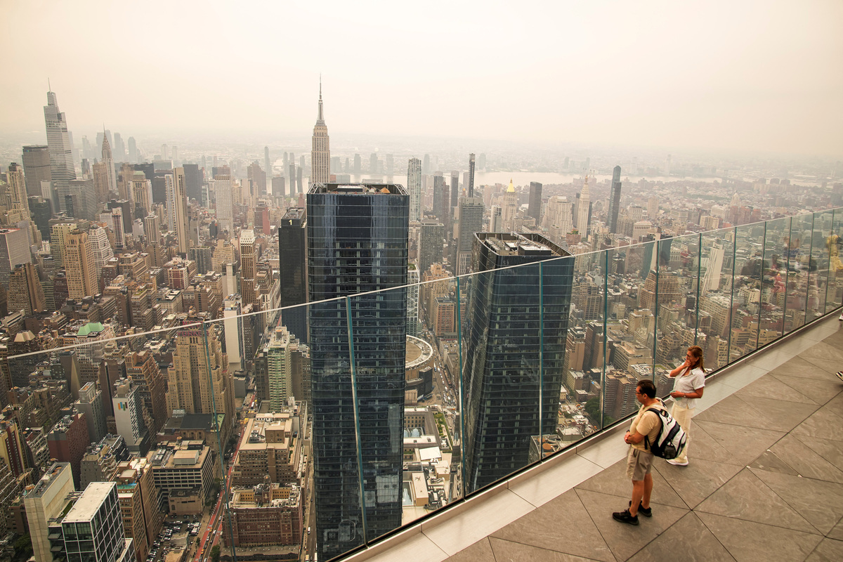 People visit the Edge observation deck as the New York City skyline and the Empire State Building are seen through a cover of wildfire smoke in New York City, U.S., July 16, 2026. REUTERS/Eduardo Munoz