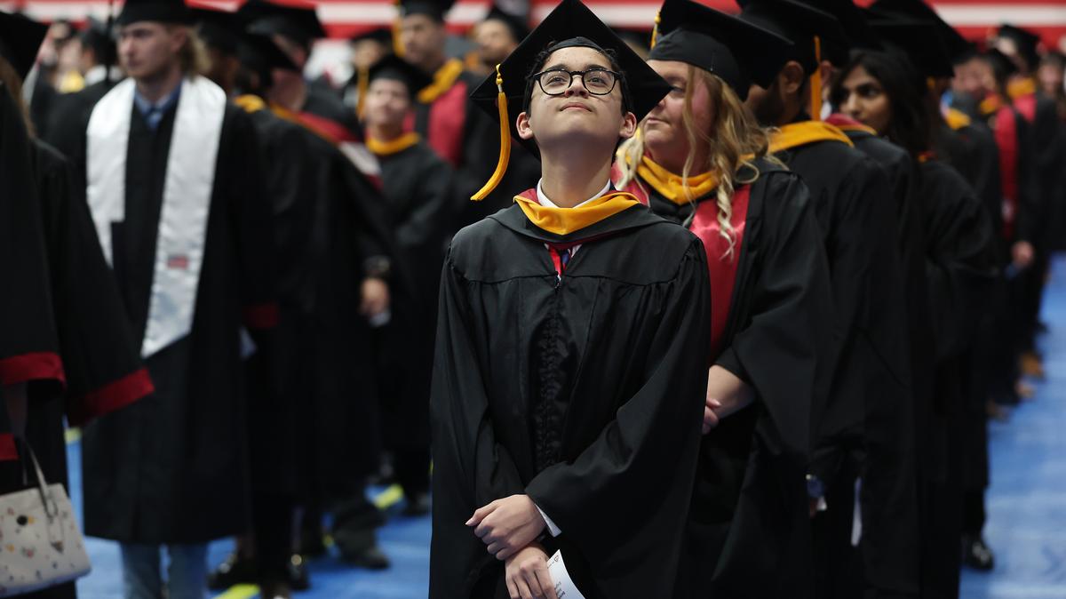 Benyamin Bamburac, 15, stands in line with other graduates before walking into the fieldhouse to begin Lewis University’s graduation ceremony in Romeoville on May 15, 2026. Bamburac graduated with a master's degree in computer science.