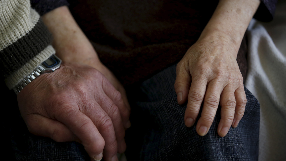 FILE PHOTO: A man holds hands with his 68-year-old wife, who was diagnosed with dementia 11 years ago, on a sofa at their home in Kawasaki, south of Tokyo, Japan, April 6, 2016. REUTERS/Issei Kato/File Photo