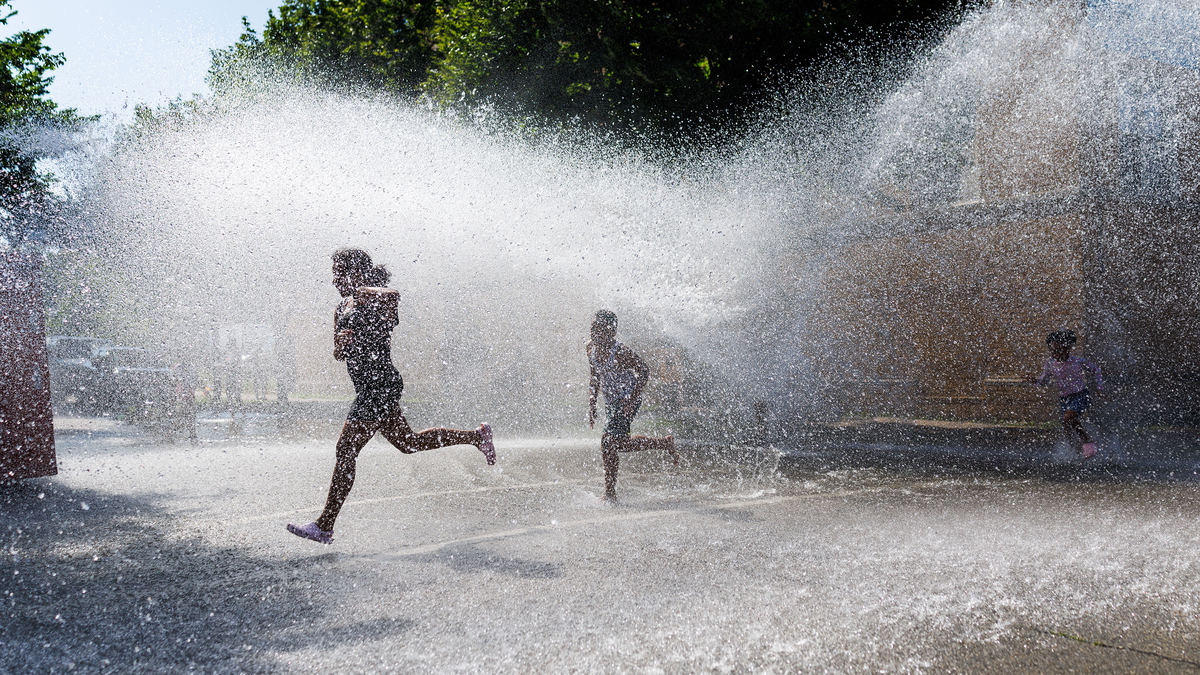 Children play in an open fire hydrant in the Garfield Park neighborhood of Chicago on a hot June 29, 2026.
