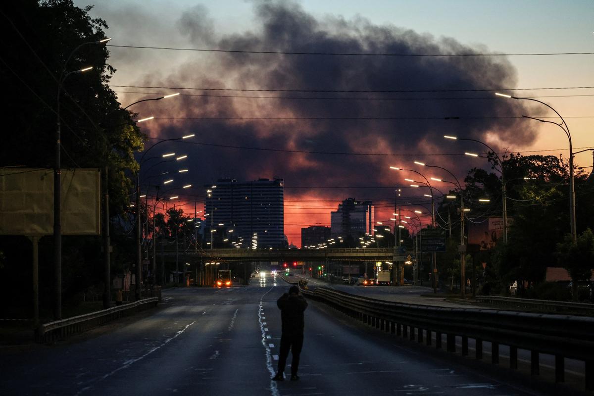 A man takes a picture of a street as smoke rises in the background after an overnight Russian missile and drone strike, amid Russia's attack on Ukraine, in Kyiv, Ukraine June 2, 2026. REUTERS/Alina Smutko