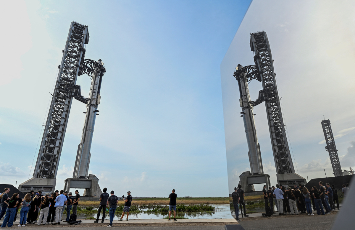 SpaceX employees are reflected in the side panel of a Tesla Cyber Truck as they gather near the Starship and Super Heavy v3 Booster at pad 2 before its 13th test flight from the SpaceX launch complex in Starbase, Texas, U.S., July 16, 2026. REUTERS/Steve Nesius
