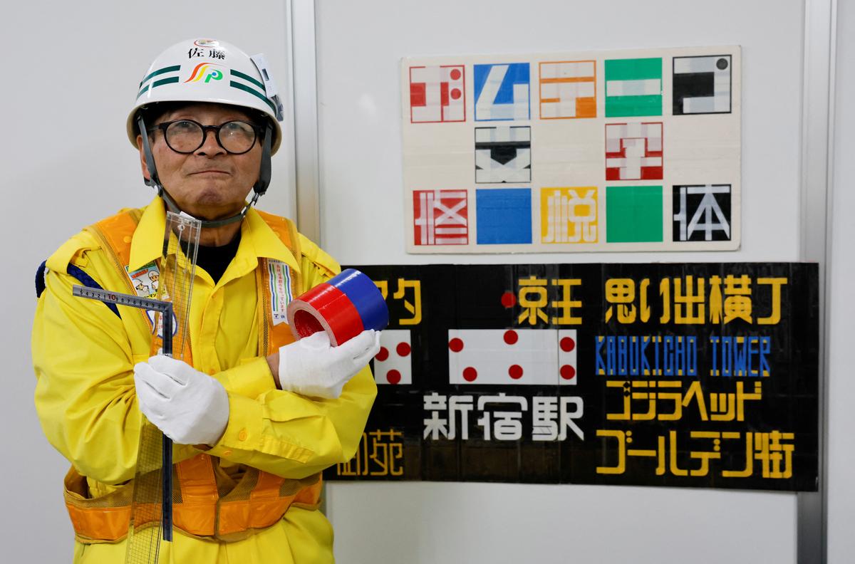 Shuetsu Sato, a security guard whose handmade duct-tape signs have gained widespread recognition, poses with duct-tape signs which he made at a security company office where he works, in Tokyo, Japan, May 1, 2026. REUTERS/Kim Kyung-Hoon