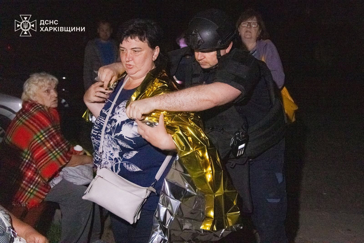 An emergency employee covers a woman with a thermal blanket at the site of a residential area damaged during overnight Russian missile and drone strikes, amid Russia's attack on Ukraine, in Kharkiv region, Ukraine June 9, 2026. Press service of the State Emergency Service of Ukraine in Kharkiv region/Handout via REUTERS