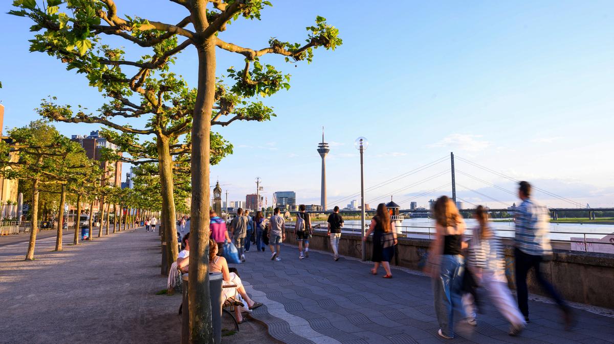 People walk at the promenade by the river Rhine with the skyline in the background including the Rheinturm in Duesseldorf, Germany, May 13, 2024. REUTERS/Jana Rodenbusch