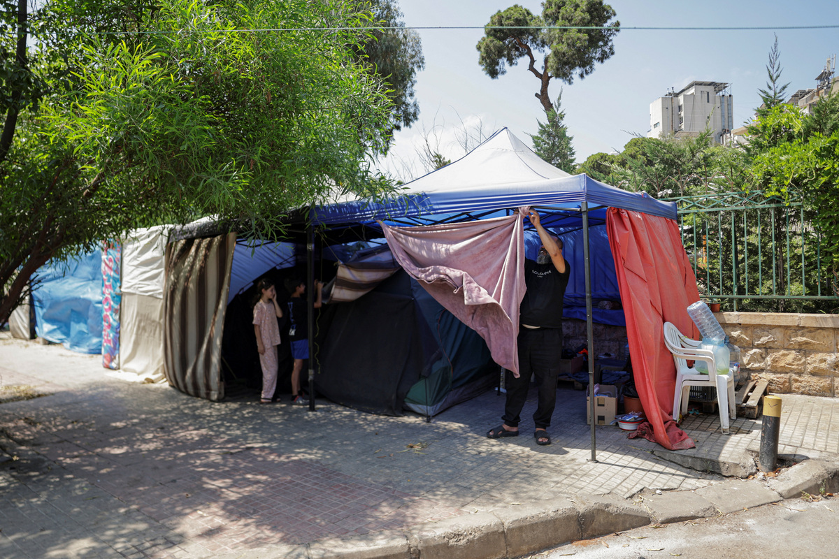 A man packs his belongings on a sidewalk in Beirut, where he and his family have been living in a tent, as he prepares to return home following an interim deal between the U.S. and Iran, in Beirut, Lebanon, June 24, 2026. REUTERS/Khalil Ashawi
