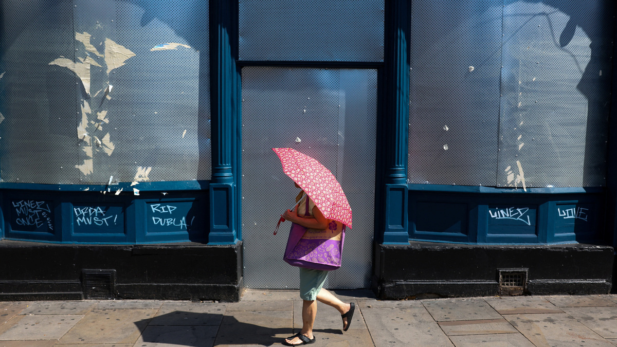 A woman walks with an umbrella to shelter from the sun as Britain experiences record temperatures during a heatwave in Fulham, London, Britain, June 26, 2026. REUTERS/Kevin Coombs