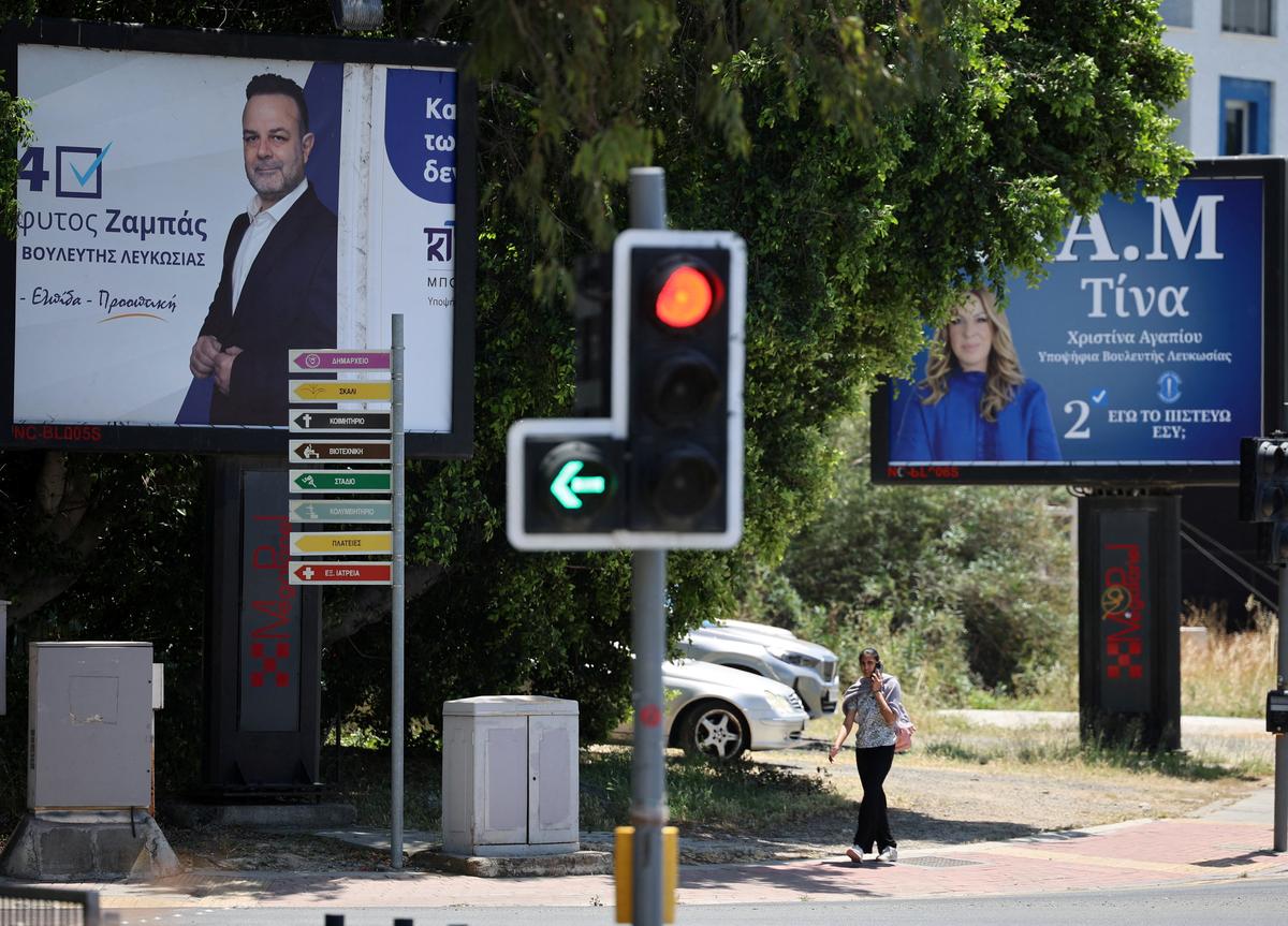 A woman walks next to posters of candidates of Cyprus' parliamentary election on May 24, in Nicosia, Cyprus May 20, 2026. REUTERS/Yiannis Kourtoglou