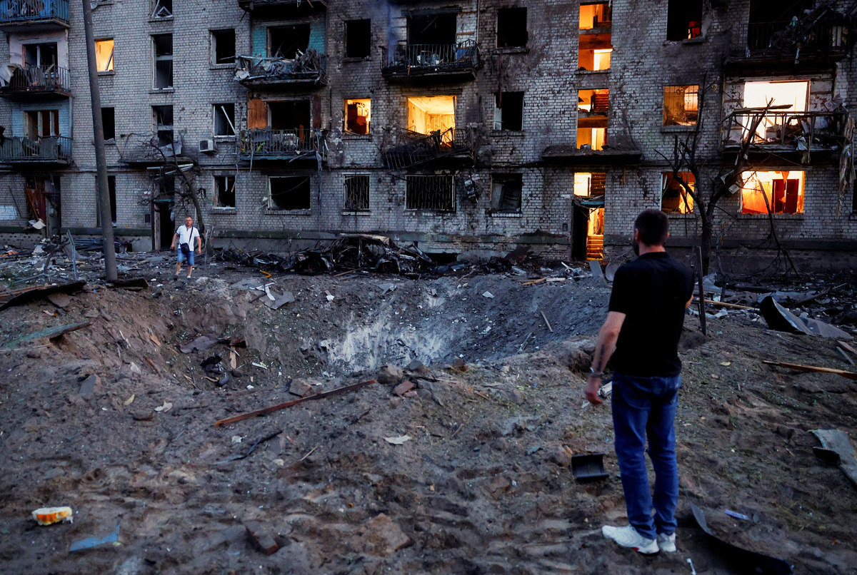Residents stand next to a crater formed at a site during overnight Russian missile and drone strikes, amid Russia’s attack on Ukraine, in Kyiv, Ukraine, July 2, 2026. REUTERS/Valentyn Ogirenko